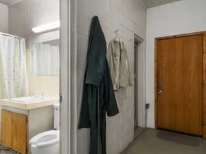 Bathroom featuring concrete flooring, vanity, and toilet.