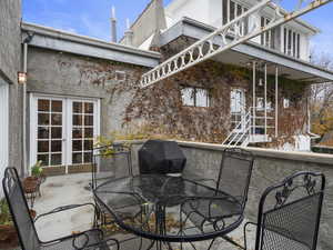 View of patio featuring a grill and french doors to second level. Note the pigeon coop above the property!