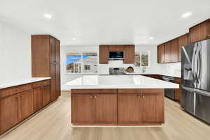 Kitchen with sink, light hardwood / wood-style floors, a kitchen island, and stainless steel appliances