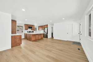 Kitchen featuring a kitchen island, stainless steel appliances, a textured ceiling, and light wood-style flooring