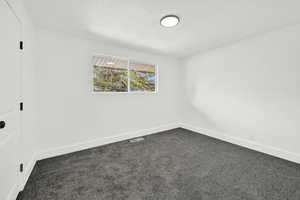 Primary room featuring a textured ceiling and gray carpet