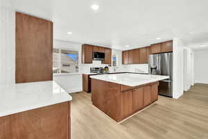 Kitchen with appliances with stainless steel finishes, backsplash, sink, a center island, and  wood-style floors