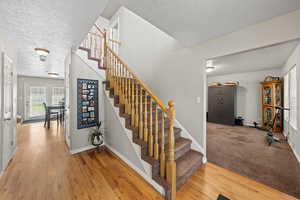 Staircase with hardwood / wood-style floors and a textured ceiling