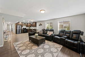 Living room with a textured ceiling and light hardwood / wood-style flooring