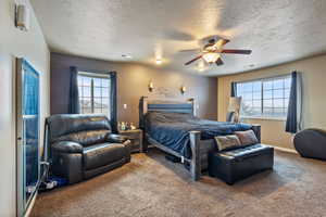 Master bedroom featuring multiple windows, ceiling fan, and a textured ceiling