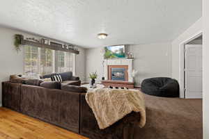 Living room with hardwood / wood-style floors, a fireplace, and a textured ceiling