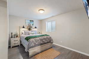 Bedroom with a textured ceiling and dark hardwood / wood-style flooring