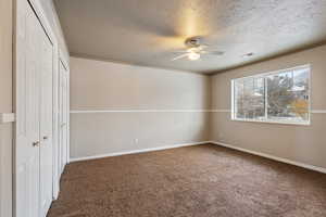 Unfurnished bedroom featuring two closets, crown molding, ceiling fan, a textured ceiling, and carpet floors