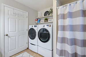 Laundry/Bathroom area with light tile patterned flooring and washer and dryer