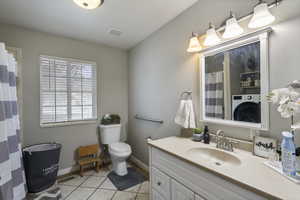 Bathroom featuring tile patterned flooring, washer / dryer, vanity, and toilet