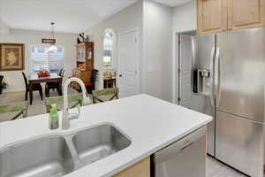 Kitchen featuring pendant lighting, light brown cabinetry, sink, and appliances with stainless steel finishes