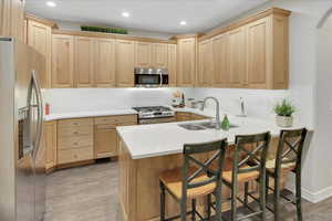 Kitchen with a kitchen breakfast bar, light brown cabinets, kitchen peninsula, and stainless steel appliances