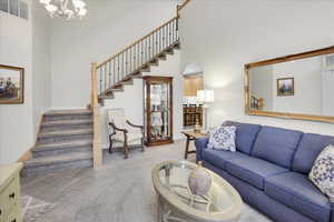 Carpeted living room with a high ceiling and a chandelier