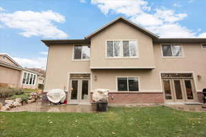 Rear view of house featuring a lawn and french doors