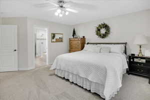 Bedroom featuring ensuite bathroom, ceiling fan, and light carpet