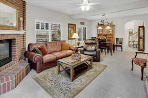 Living room featuring light carpet,  notable chandelier, a fireplace