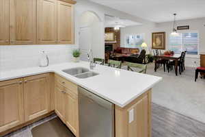 Kitchen featuring kitchen peninsula, a brick fireplace, sink, dishwasher, and hardwood / wood-style floors