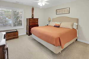 Carpeted bedroom featuring ceiling fan