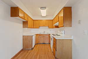 Kitchen featuring sink, white appliances, and light wood-type flooring