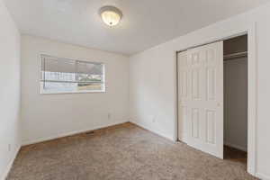 Unfurnished bedroom featuring carpet, a textured ceiling, and a closet