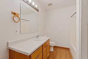 Full bathroom with wood-type flooring, vanity, toilet, and shower / washtub combination