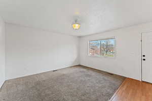 Empty room with hardwood / wood-style floors and a textured ceiling