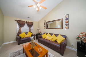 Living room featuring light colored carpet, vaulted ceiling, and ceiling fan