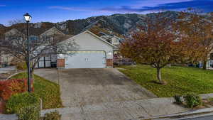 Front facade with a mountain view, a garage, and a yard