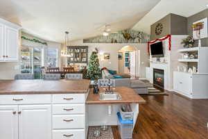 Kitchen featuring butcher block counters, ceiling fan, dark hardwood / wood-style flooring, vaulted ceiling, and white cabinets