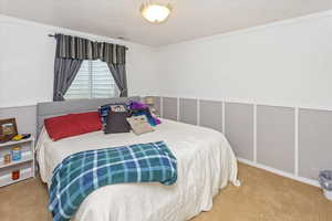 Bedroom with crown molding and light carpet