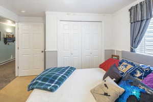 Bedroom with carpet flooring, ornamental molding, baseboard heating, and a closet