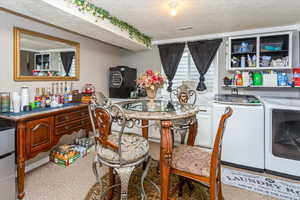 Carpeted dining room with a textured ceiling and separate washer and dryer