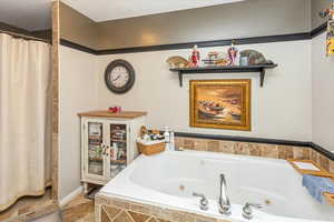 Bathroom featuring a textured ceiling and a relaxing tiled tub