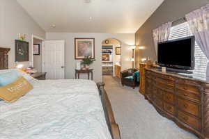 Bedroom with multiple windows, light carpet, and lofted ceiling