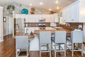 Kitchen featuring white cabinets, lofted ceiling, and stainless steel appliances