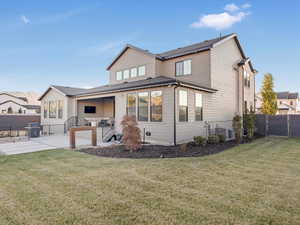 Rear view of house with central AC unit, a patio area, and a lawn