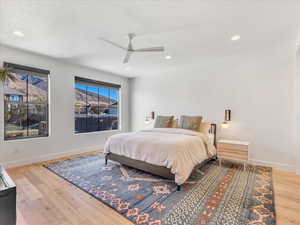 Bedroom featuring hardwood / wood-style floors, ceiling fan, and a textured ceiling