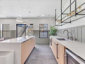 Kitchen with light brown cabinetry, a textured ceiling, wine cooler, and sink