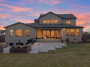 Back house at dusk with outdoor lounge area, a yard, and a patio area