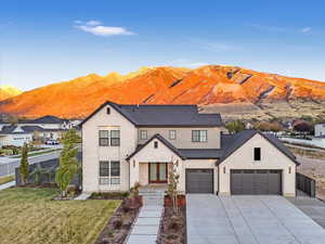 View of front of home with a mountain view, french doors, a front lawn, and a garage