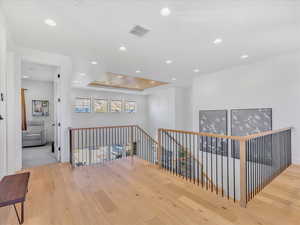 Hall with light hardwood / wood-style flooring and a tray ceiling