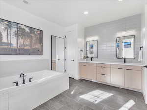 Bathroom with tile patterned flooring, vanity, a relaxing tiled tub, and plenty of natural light