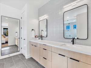 Bathroom with tile patterned floors, backsplash, vanity, and walk in shower