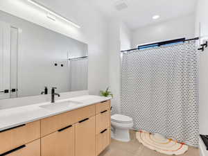 Bathroom featuring toilet, vanity, tile patterned floors, and a shower with shower curtain