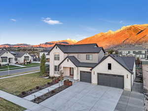 View of front of property featuring a mountain view, a garage, and a front lawn