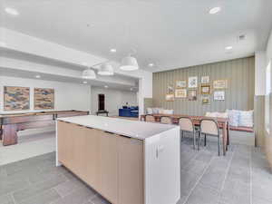 Kitchen featuring pendant lighting, a kitchen island, a textured ceiling, and light brown cabinetry