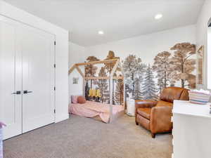 Bedroom with a closet, light colored carpet, and a textured ceiling