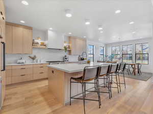 Kitchen featuring light brown cabinets, sink, light hardwood / wood-style floors, and an island with sink