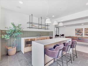 Kitchen with a center island, stainless steel oven, hanging light fixtures, and sink