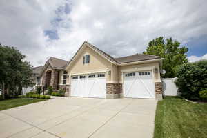 View of front facade featuring stone siding, driveway, stucco siding, an attached garage, and a tiled roof